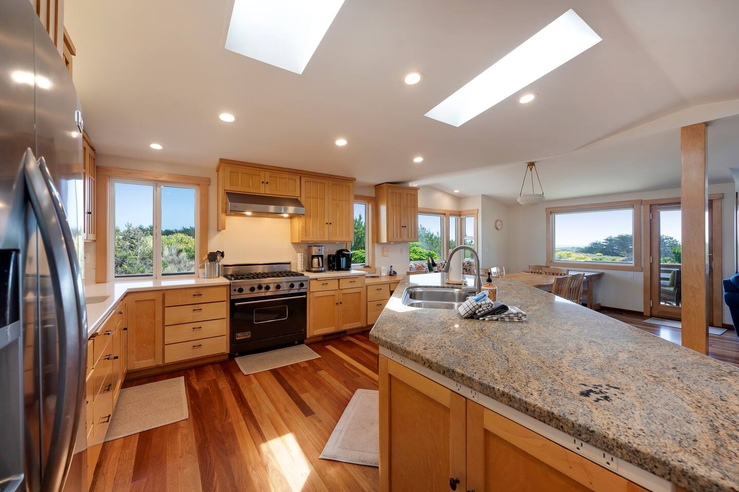 Bright gourmet kitchen with granite island, skylights, and scenic views