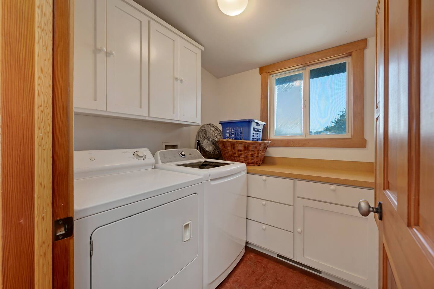 Bright laundry room with full-size washer/dryer and ample storage