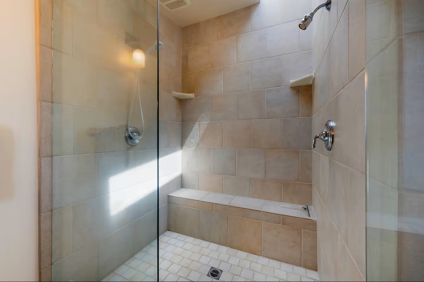 Spacious tiled walk-in shower with glass enclosure and built-in bench