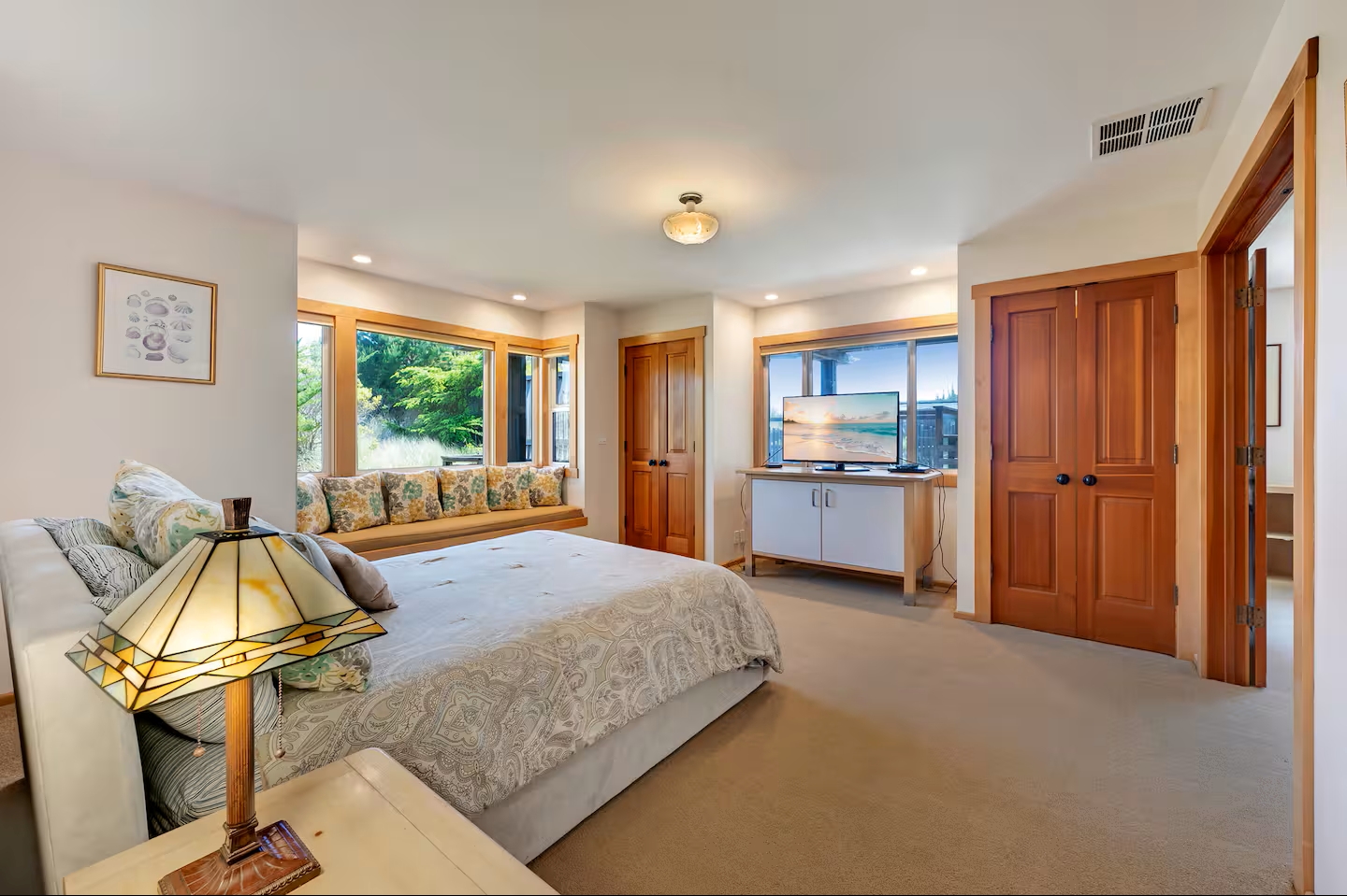 Bright, spacious bedroom with window seat, TV, and peaceful natural light