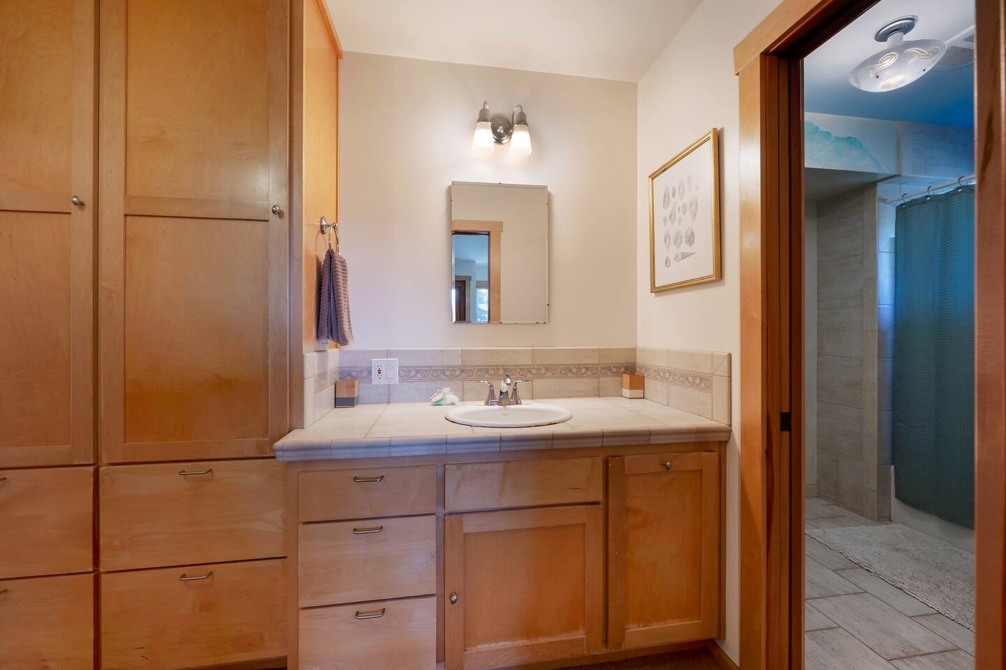 Spacious bathroom with warm wood cabinetry and ample storage