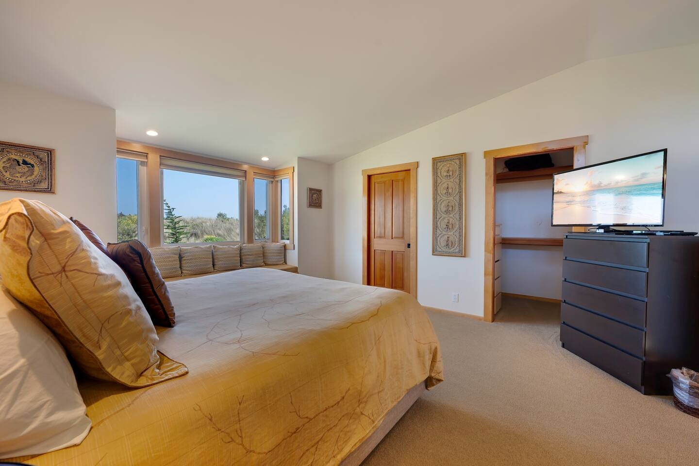 Bright bedroom with scenic views, cozy window seat, TV, and ample space
