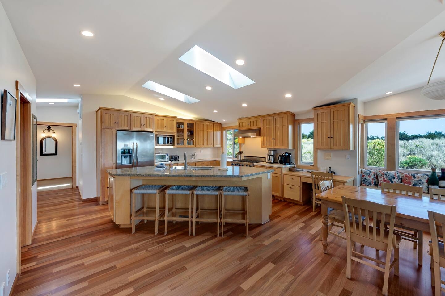 Bright open kitchen with skylights, island seating, and sunny dining area