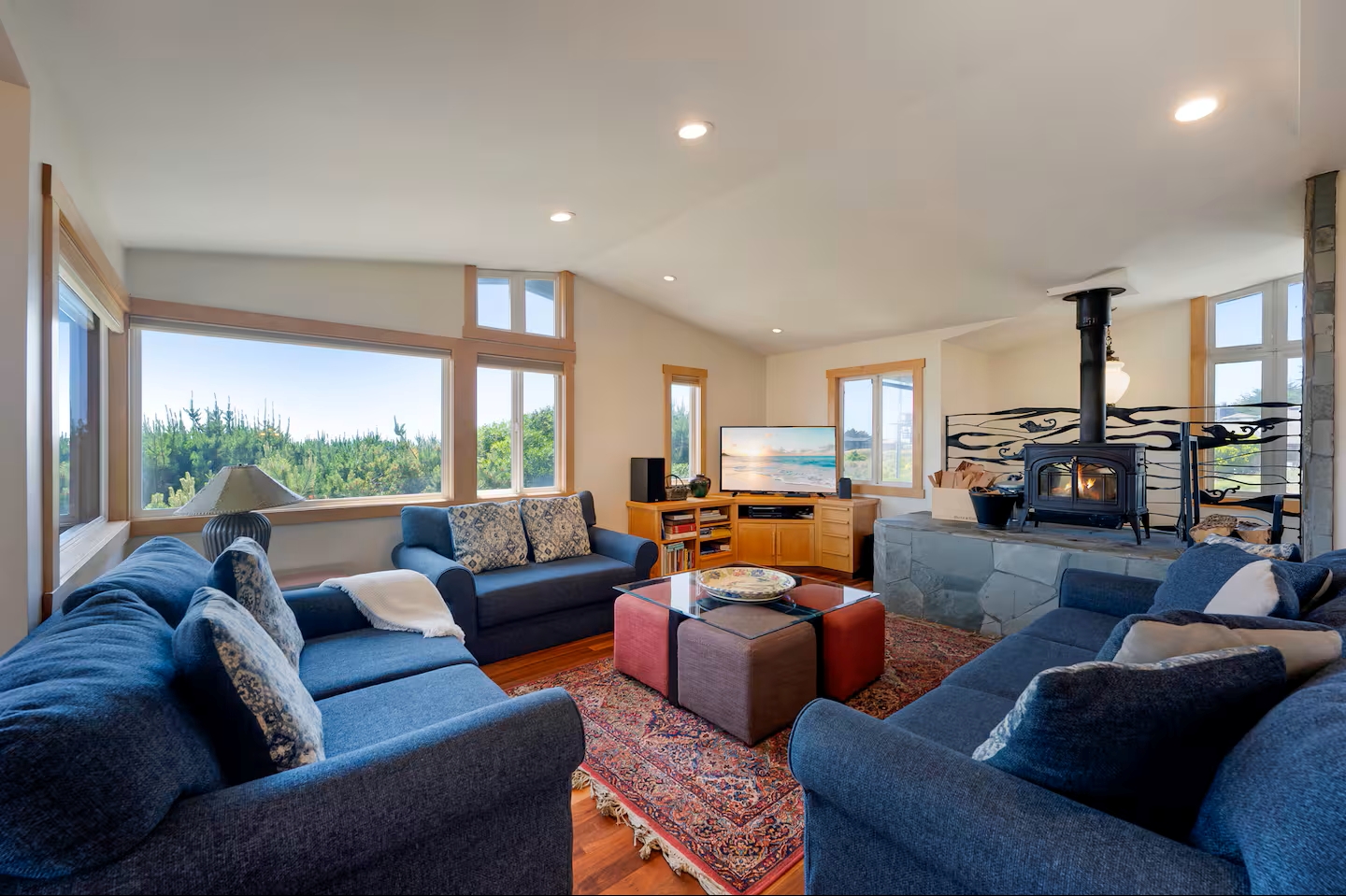 Bright, cozy living room with forest views and a charming wood stove