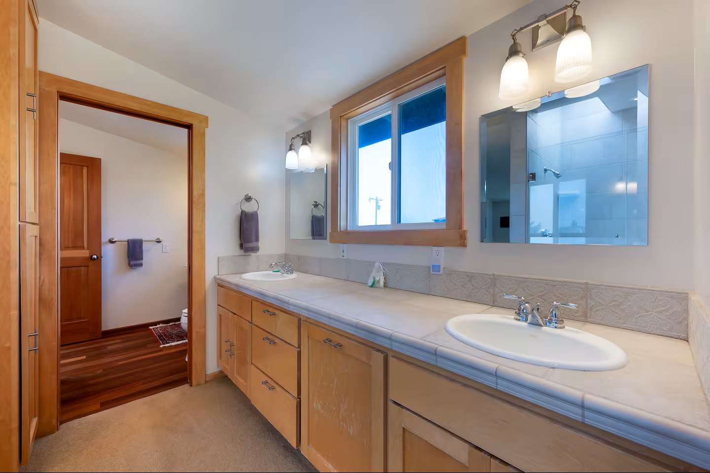 Bright double-vanity bathroom with warm wood accents and great natural light