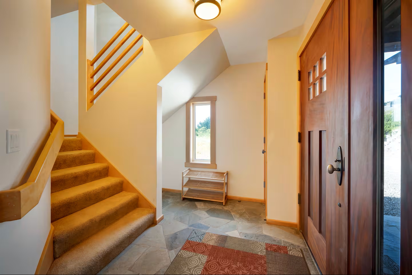 Bright entryway with slate floors, wood details, and staircase charm