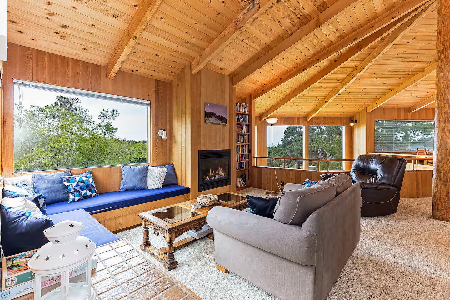 Cozy wood-lined lounge with fireplace and sweeping treetop views