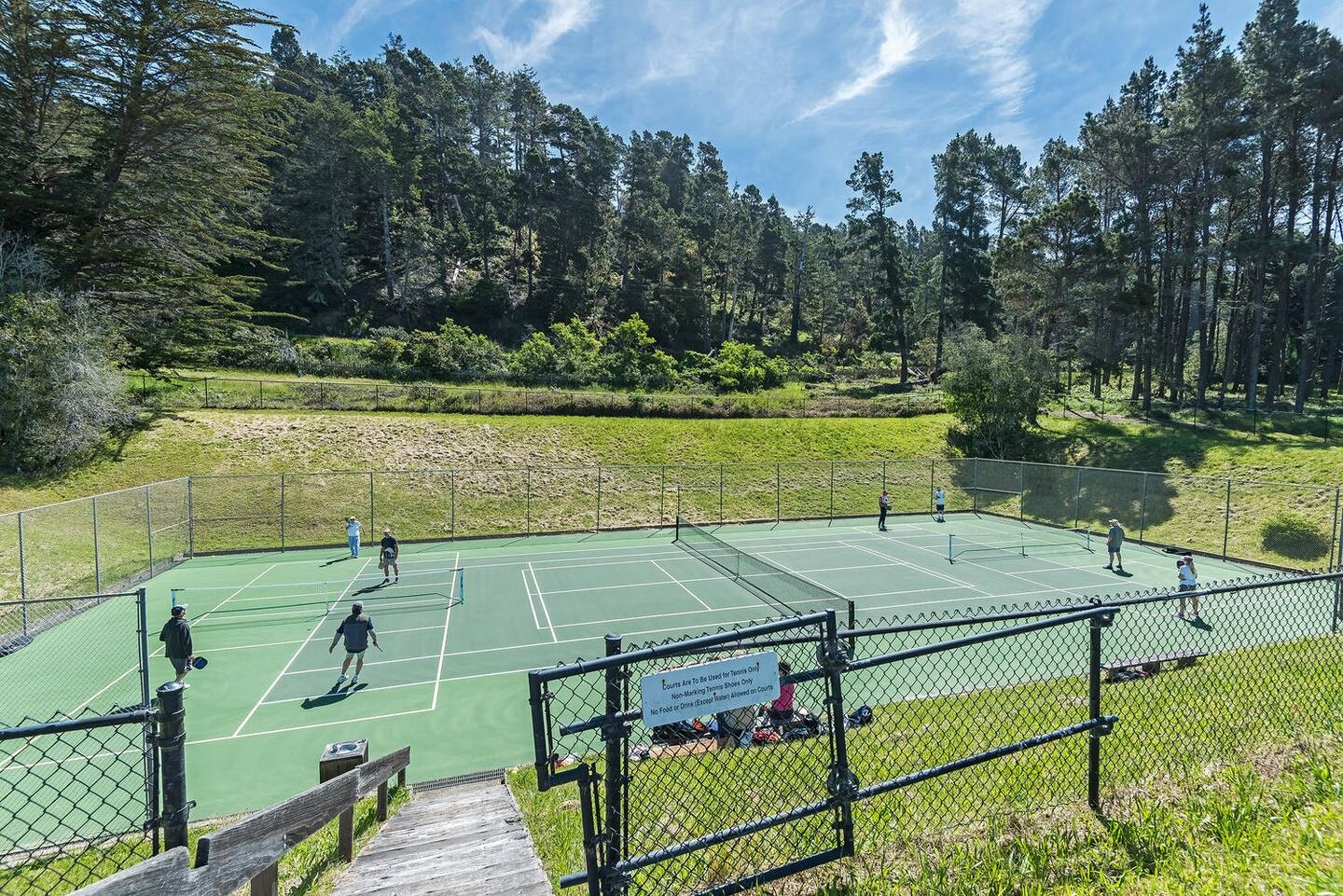 Scenic outdoor tennis courts surrounded by peaceful forest views