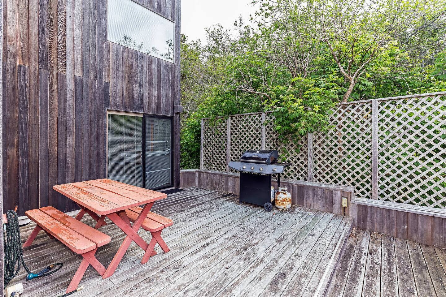 Private deck with grill and outdoor dining surrounded by greenery