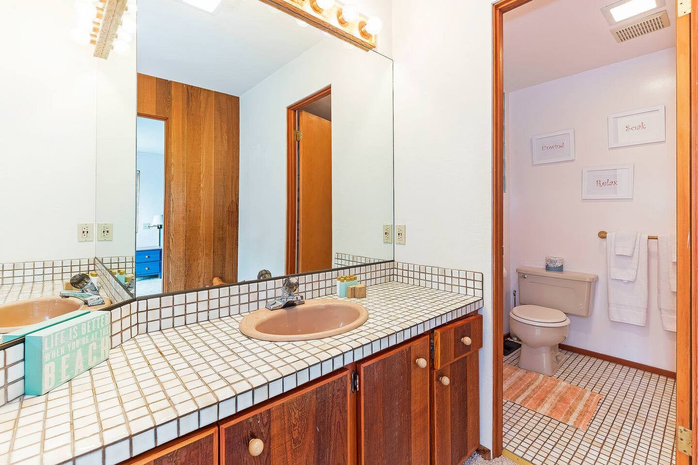 Bright bathroom with spacious vanity, large mirror, and private toilet area