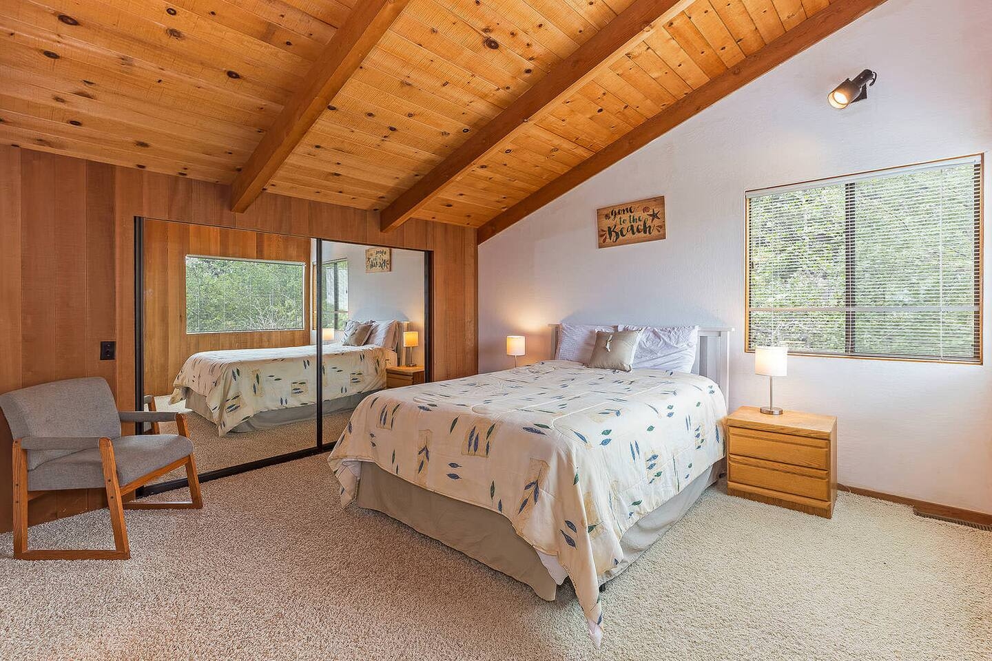 Cozy bedroom with vaulted wood ceilings and peaceful forest views
