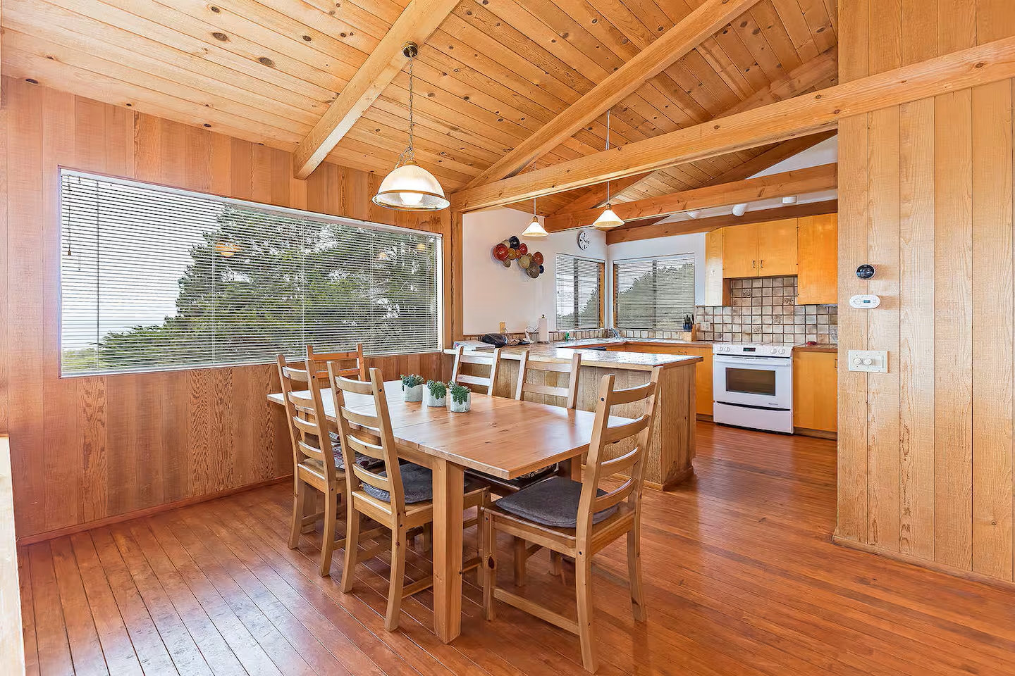Bright wood-lined dining area with vaulted ceilings and scenic views