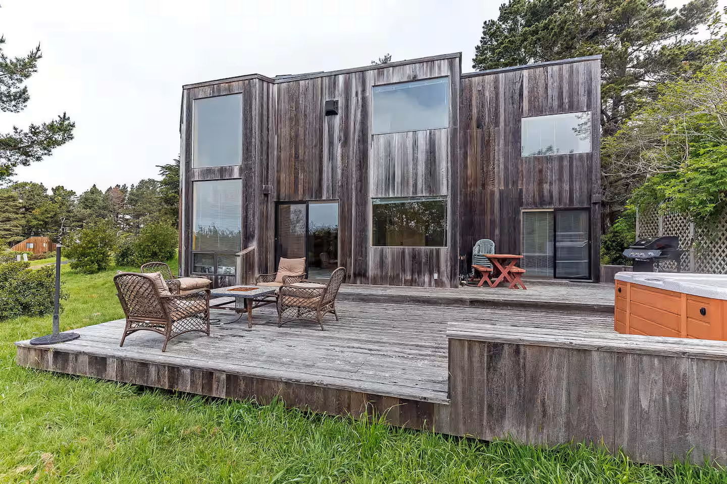 Spacious wood deck with hot tub, grill, and serene outdoor seating