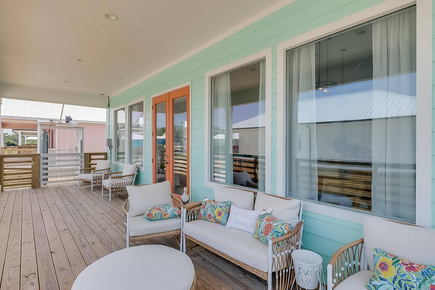Cajun Paradise front porch with mint siding, cushioned seating and water view