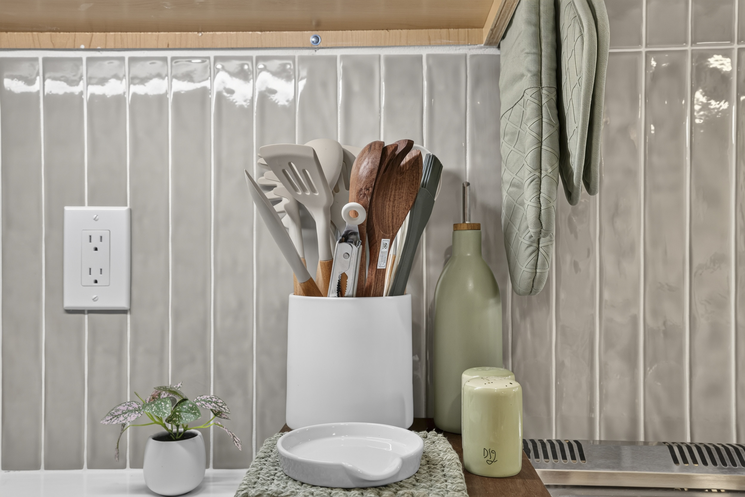 Stylish, well-stocked kitchen details with modern tile and soft sage accents