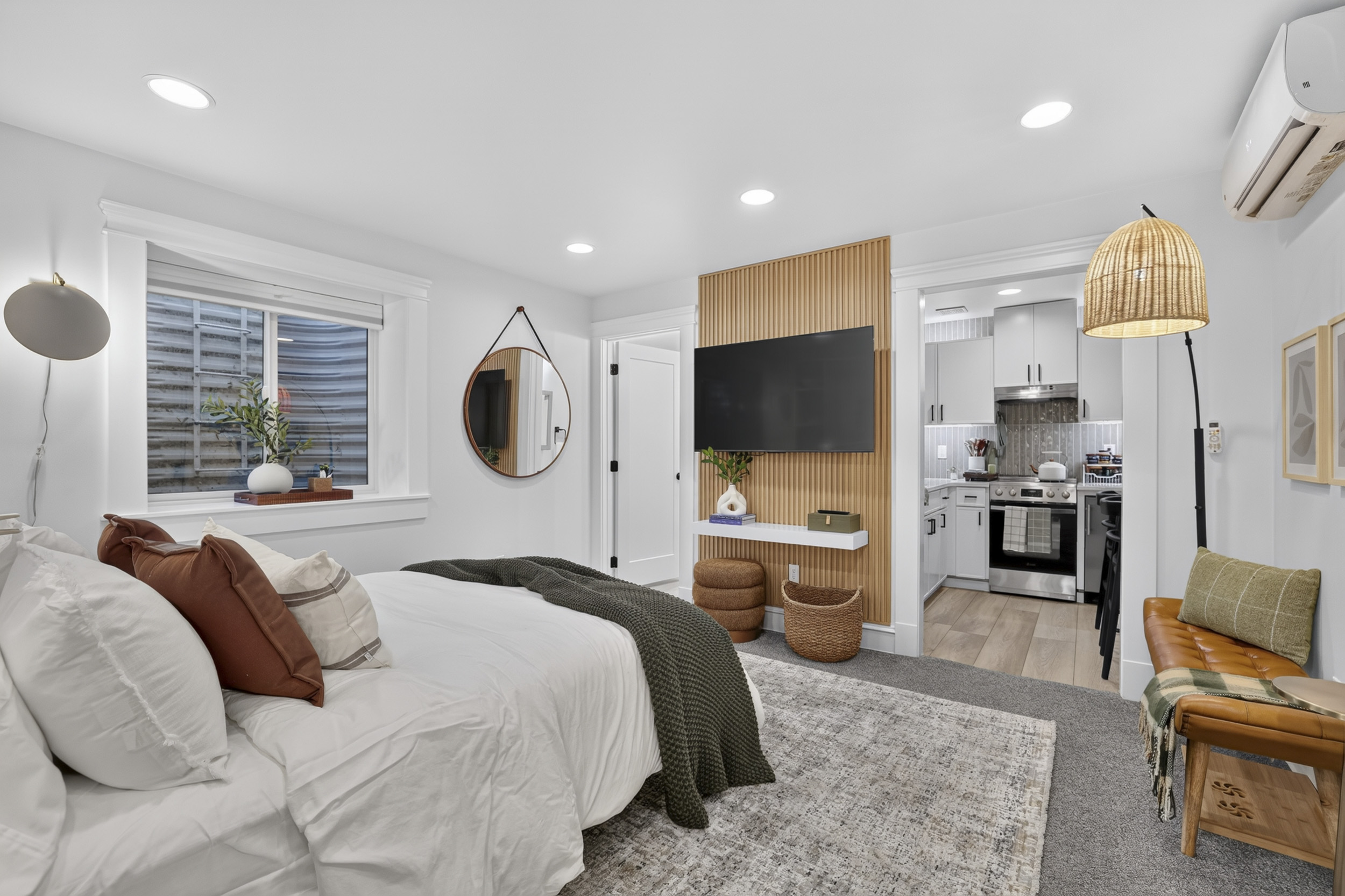 Bright, stylish studio with cozy bed, TV accent wall, and compact kitchen