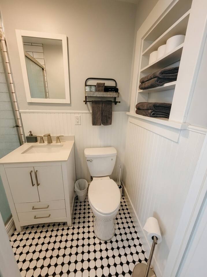 This newly remodeled full bathroom features a sleek walk-in shower with classic white subway tile, a stylish vanity with modern fixtures, and classic black-and-white patterned tile flooring for a refreshed, functional design.