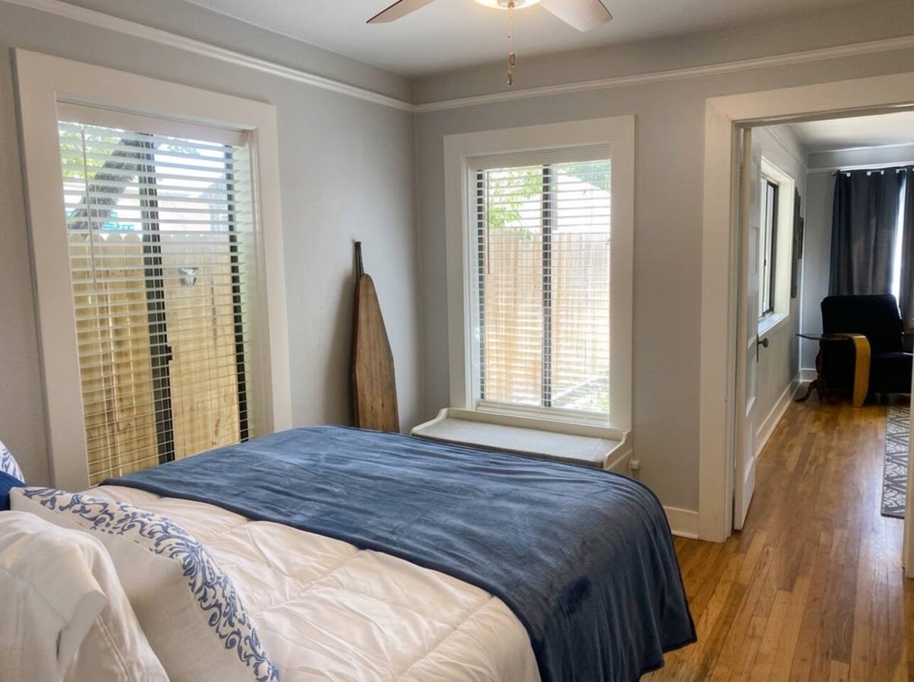 This peaceful bedroom features a comfortable queen bed, warm hardwood floors, and a ceiling fan. Bathed in natural light with ample closet storage, it offers a cozy and restful retreat for guests.