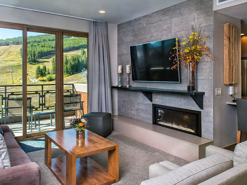 Cozy mountain-view lounge with fireplace, TV, and private balcony
