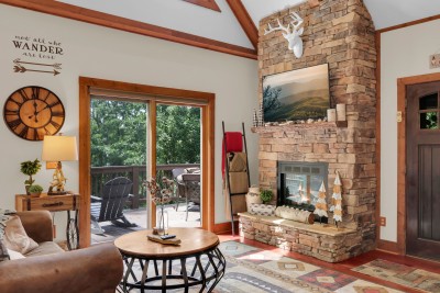 Gather in this lodge-style living room, where the stone fireplace sets a warm scene and deck access invites you to step right out into the mountain views.