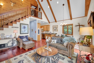 Take in the vaulted ceilings and open flow of this rustic great room, where loft stairs lead to even more space to gather—the perfect hub for mountain memories with the whole crew.
