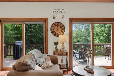 Relax in this living room with wooded views, deck seating, and easy access to the outdoor grill—perfect for firing up dinner while soaking in the mountain scenery.