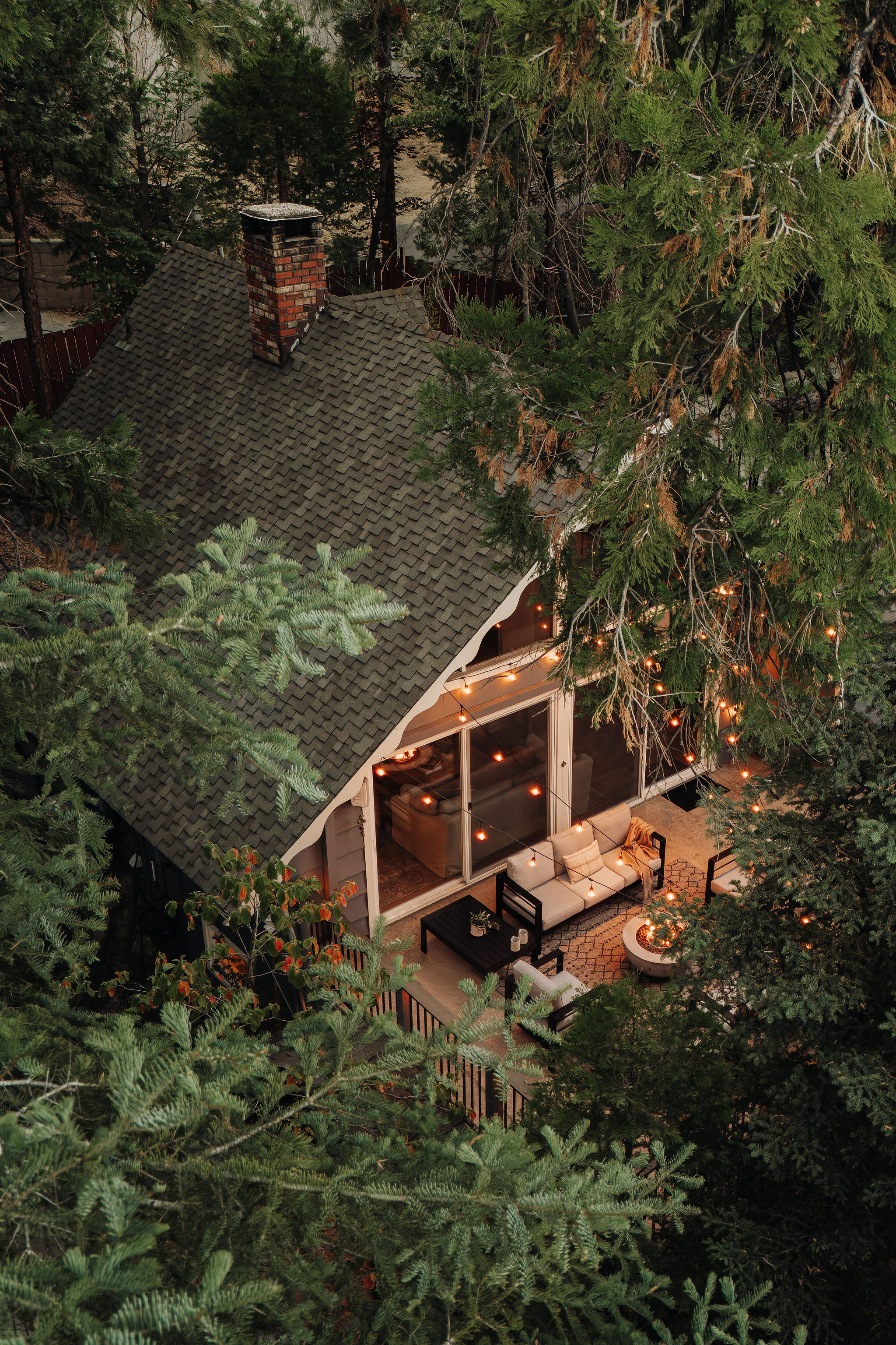 Cozy forest cabin with string lights, deck seating, and fire pit charm