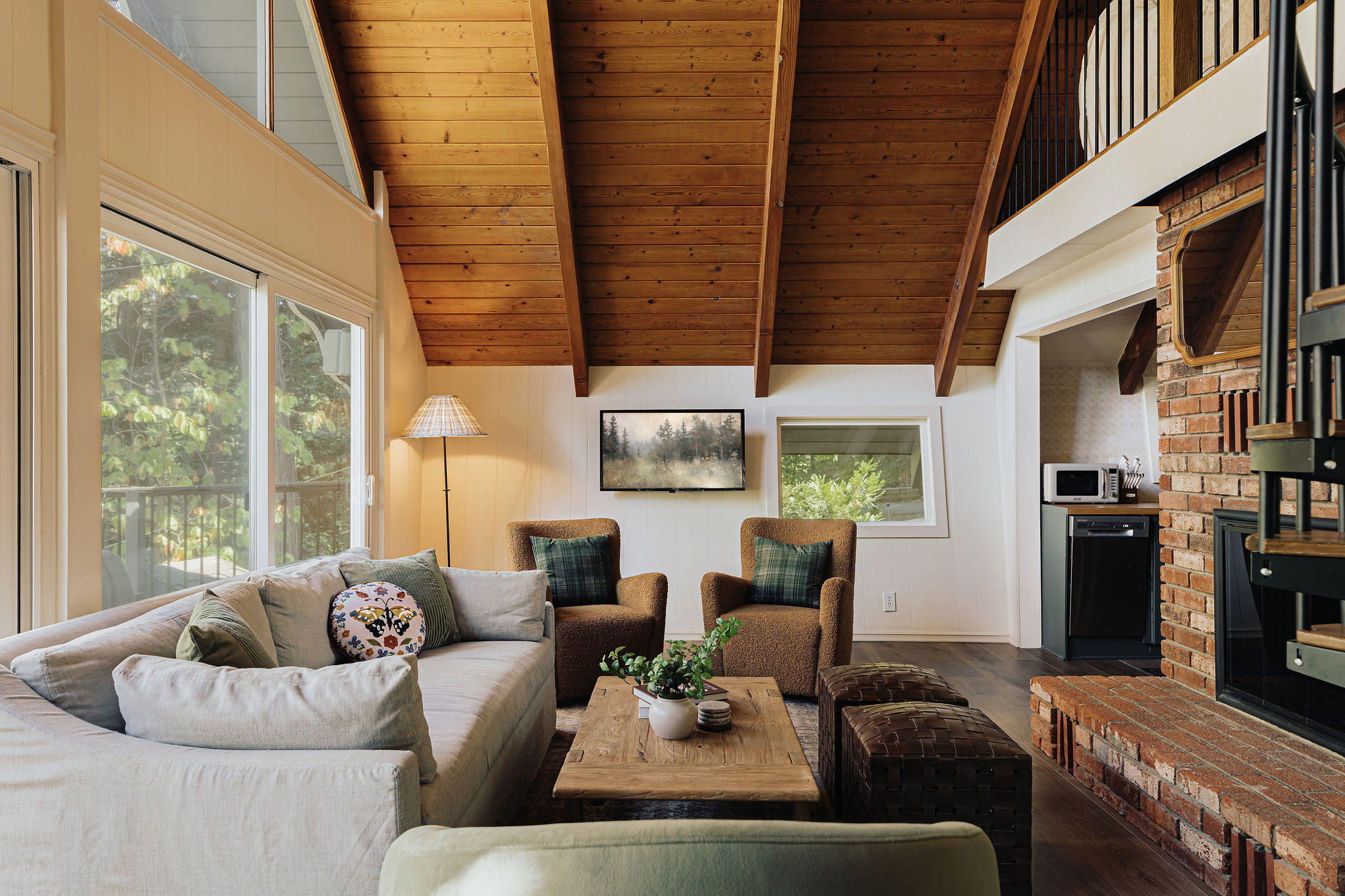 Cozy vaulted living room with brick fireplace and warm wood ceilings