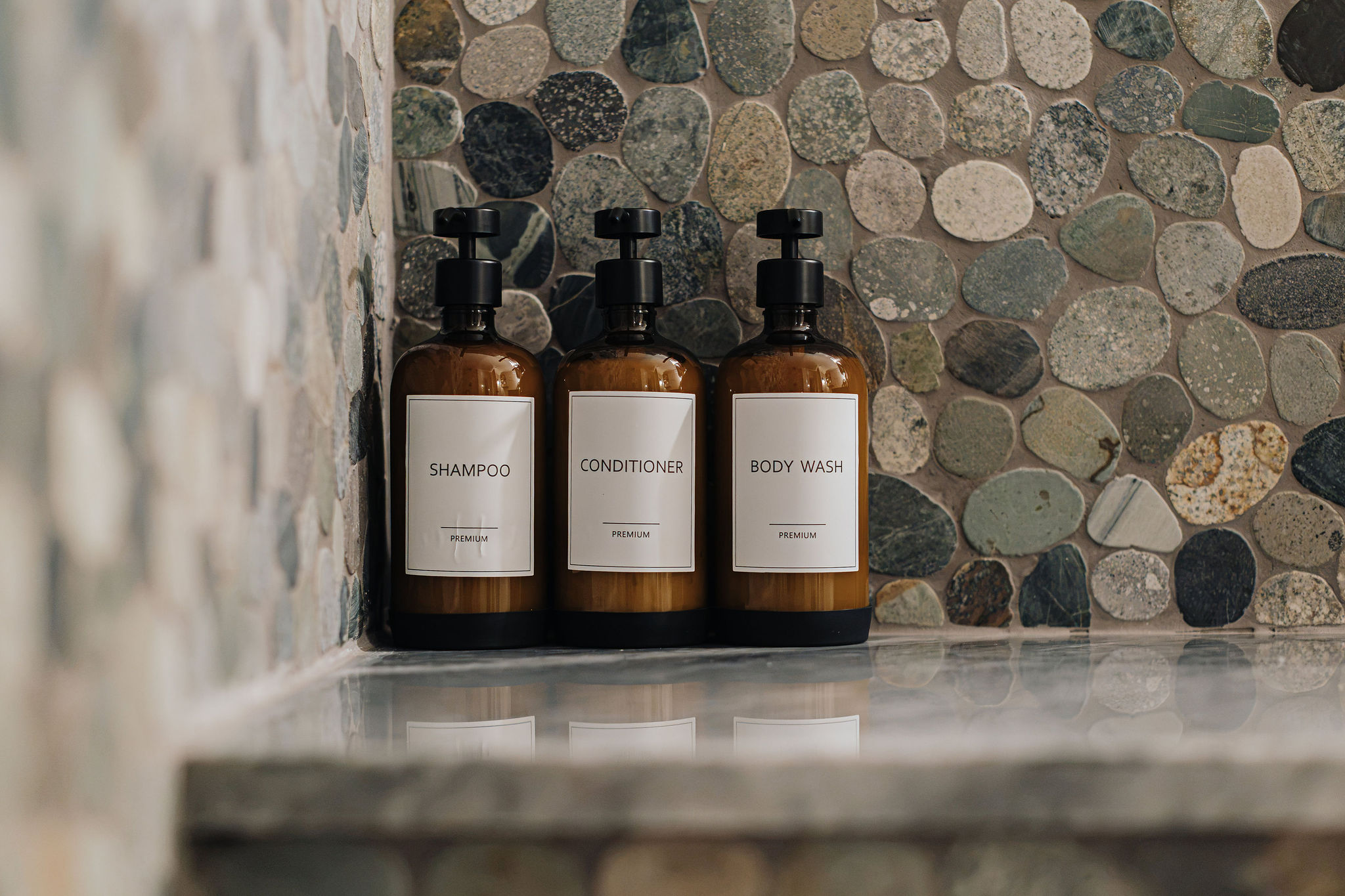 Spa-style shower with premium bath amenities and natural stone tile