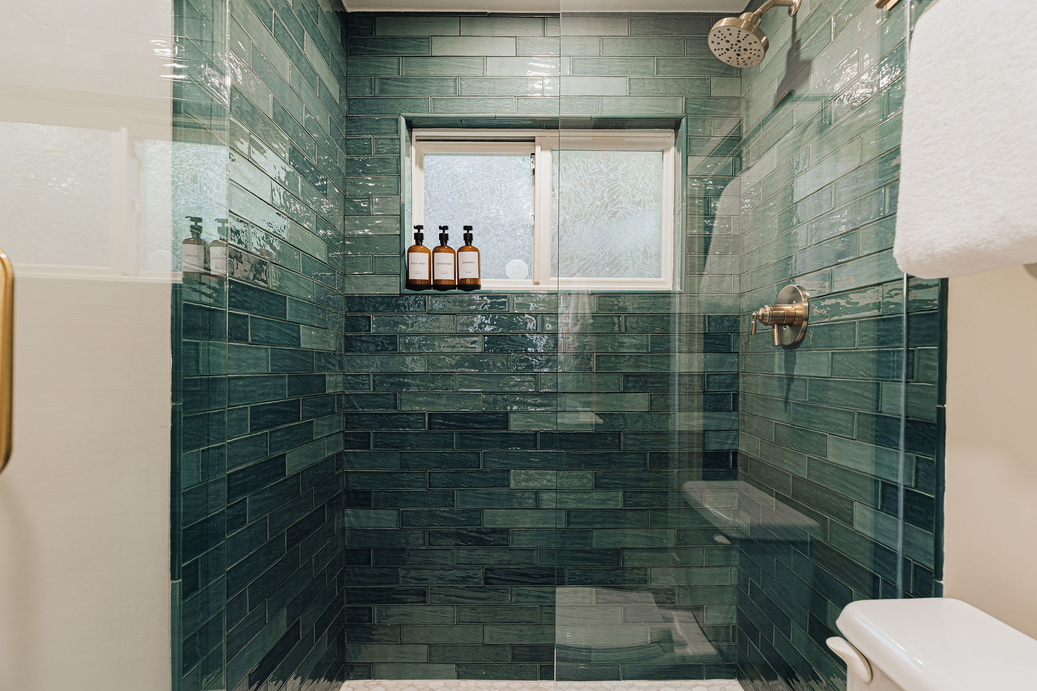 Spa-like tiled walk-in shower with brass fixtures and natural light