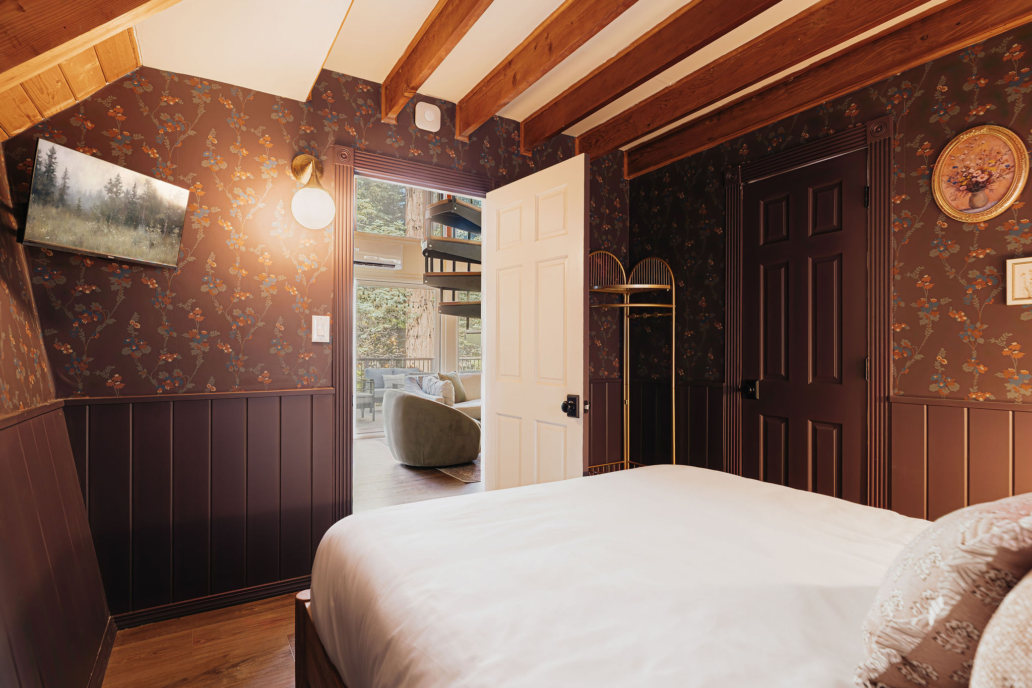 Cozy wood-beam bedroom with floral wallpaper and charming cabin style