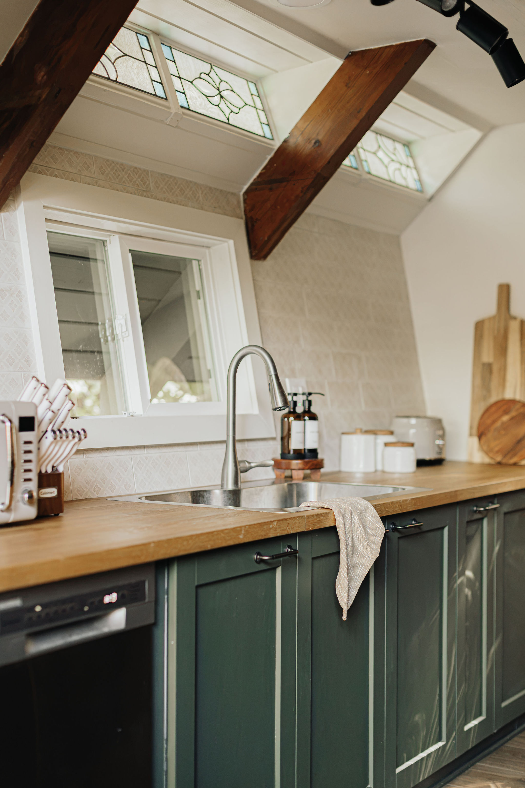Charming kitchen with stained glass, wood beams, and stylish green cabinetry