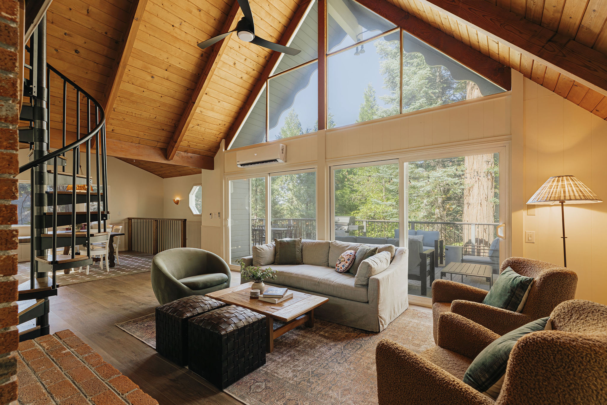 Bright mountain-style living room with vaulted ceilings and forest-view deck