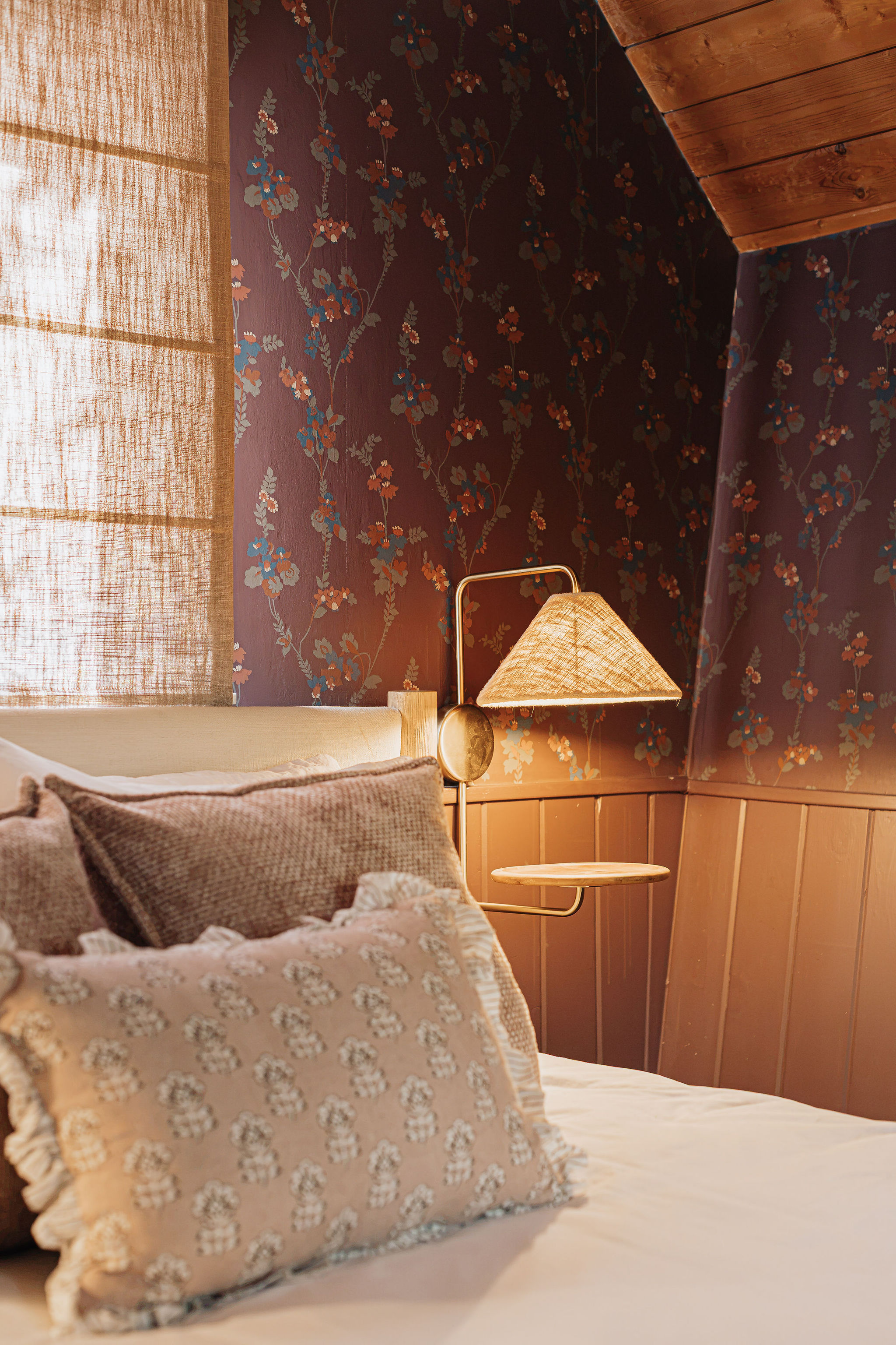 Cozy bedroom nook with floral wallpaper and warm ambient lighting