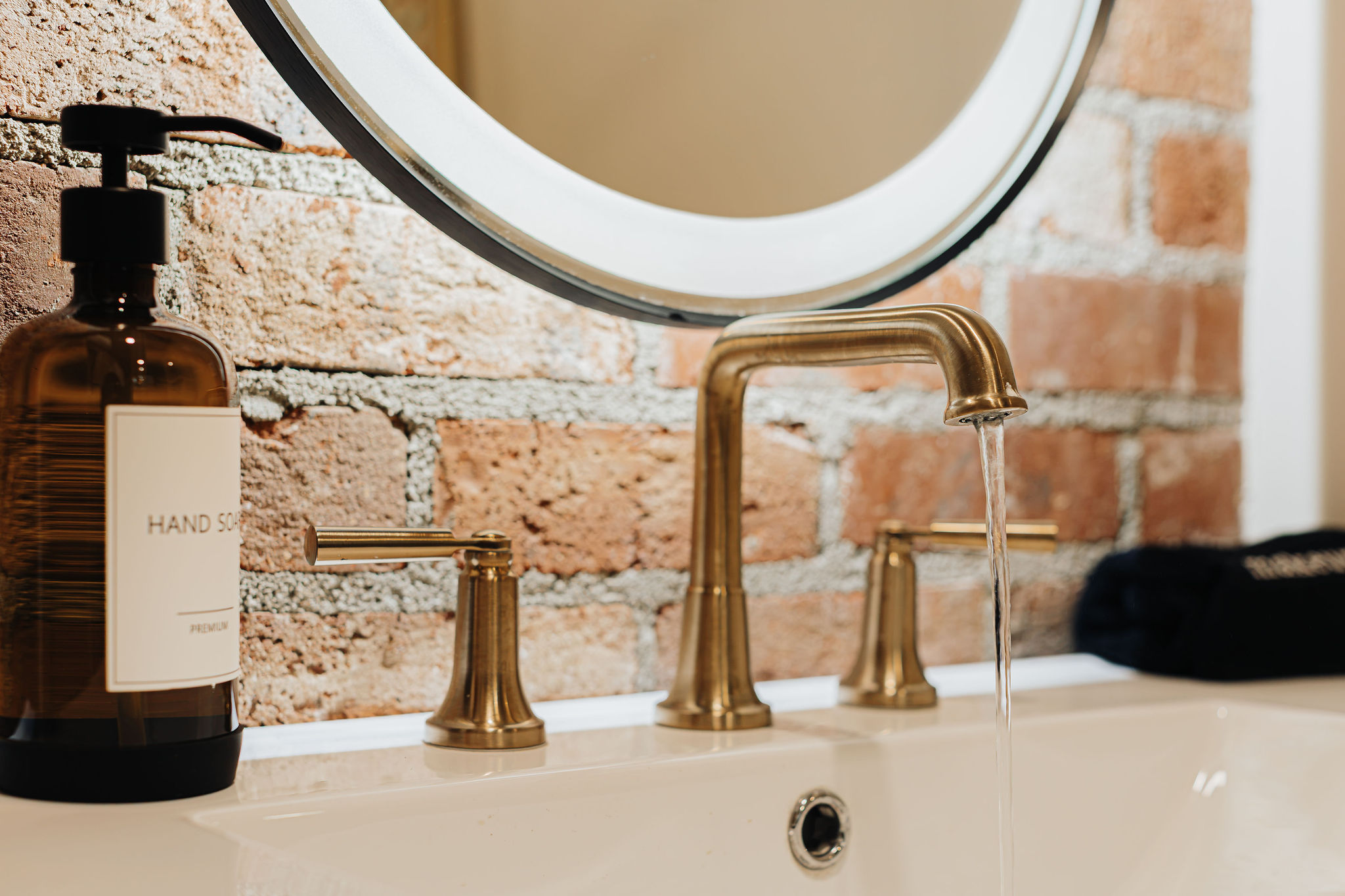 Chic bathroom vanity with brass fixtures and warm exposed brick charm