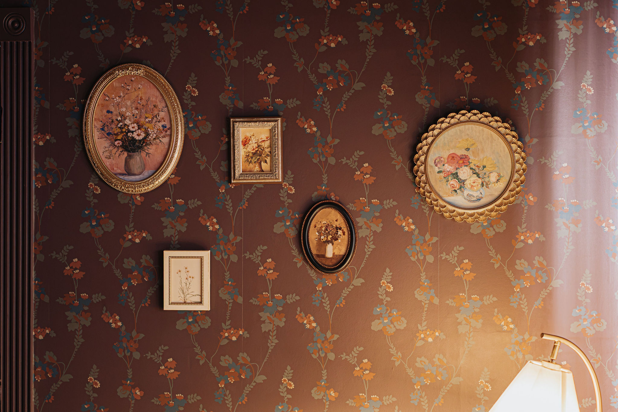 Elegant floral accent wall with vintage art and warm ambient lighting
