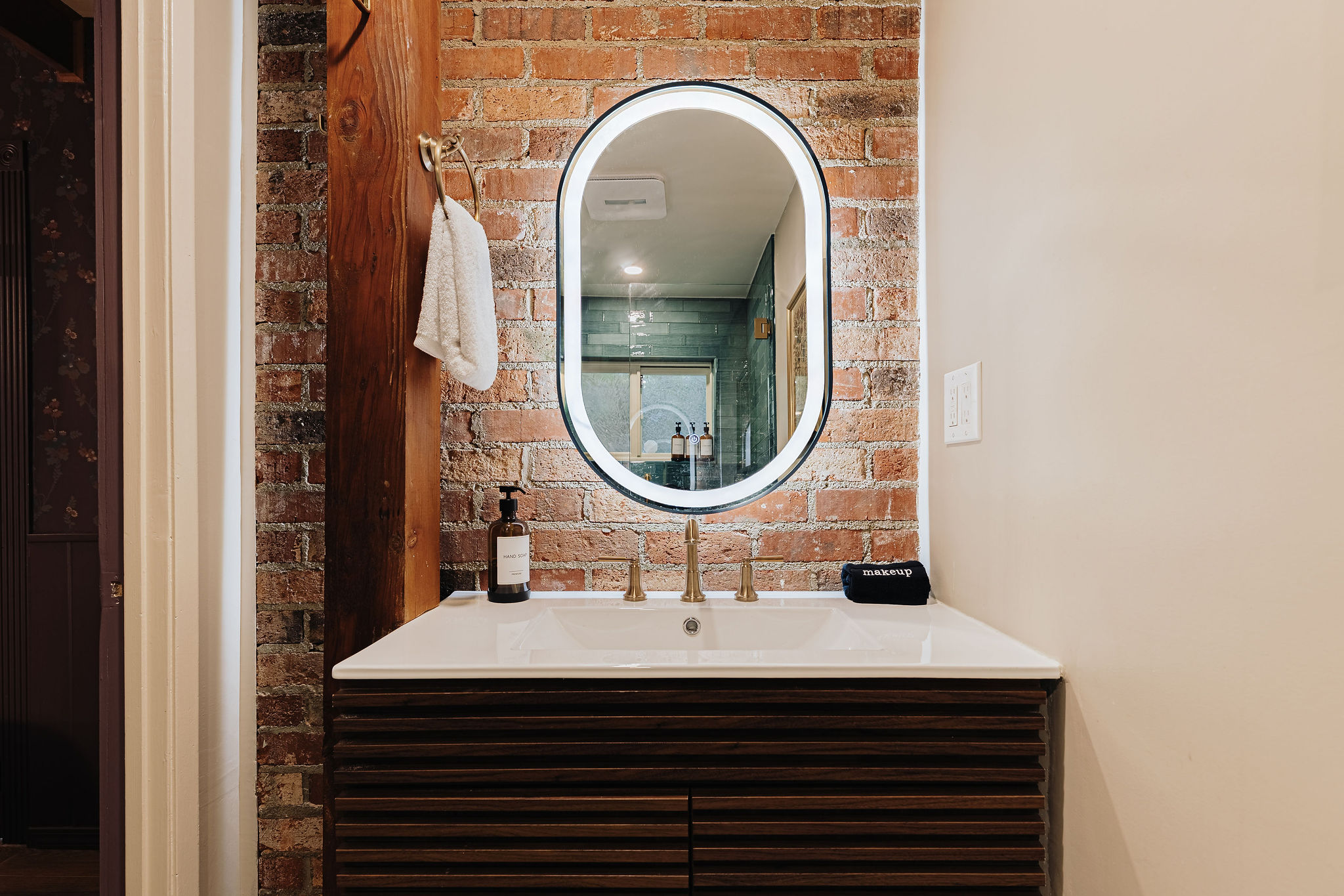 Stylish vanity with exposed brick, brass fixtures, and modern charm