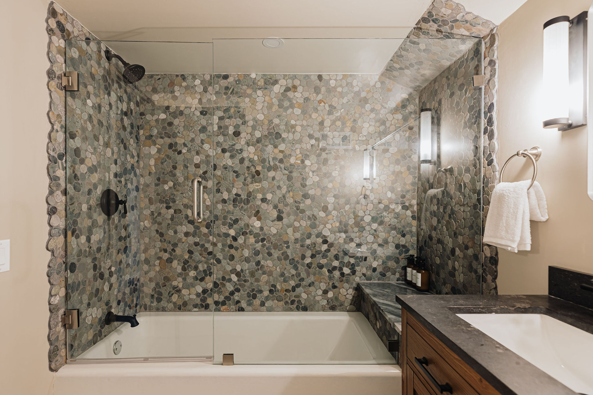Spa-style bathroom with pebble tile shower and sleek glass enclosure