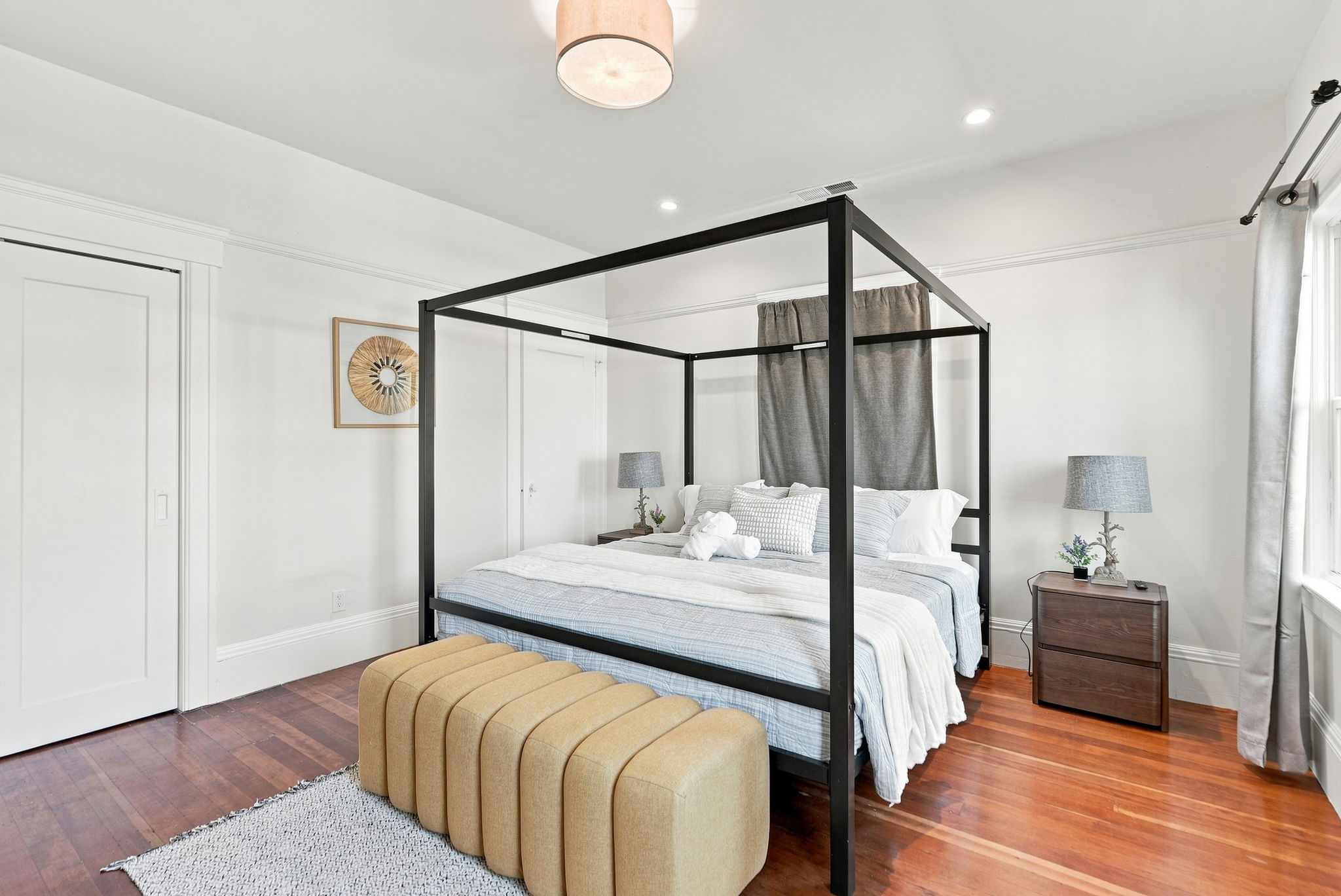 Bright bedroom with elegant four-poster bed and warm hardwood floors