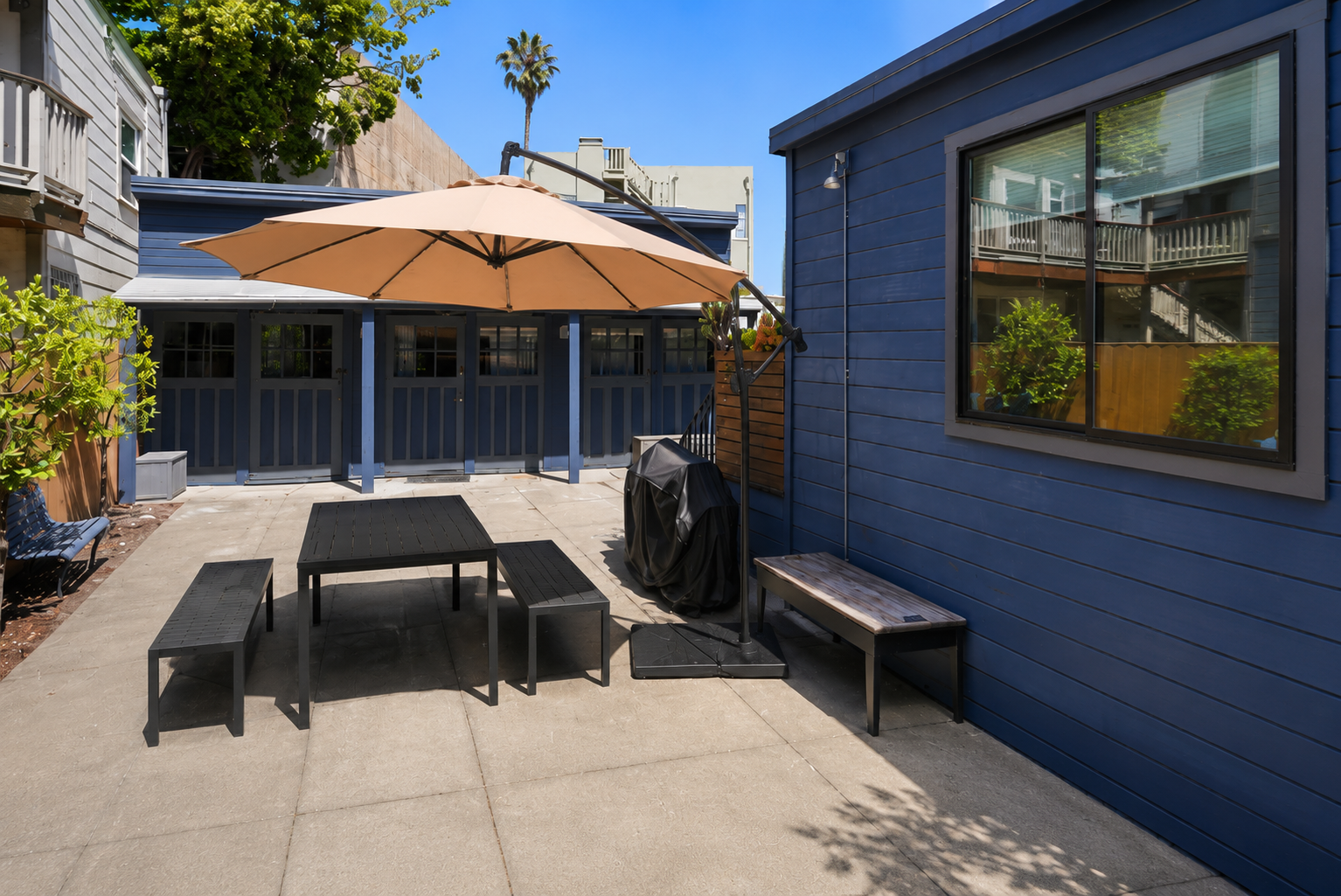 Private sunny patio with shaded dining area and grill