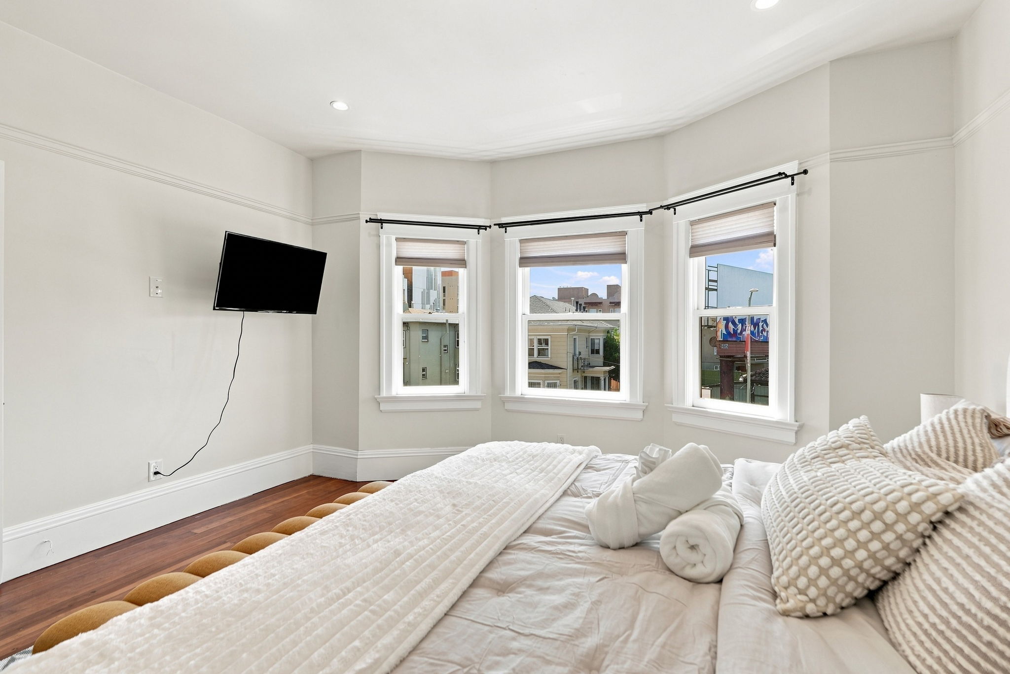 Bright bay-window bedroom with hardwood floors and cozy modern touches