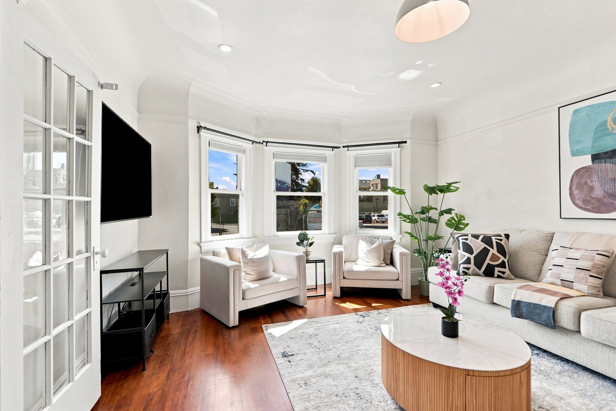 Sun-filled living room with bay windows, cozy seating, and modern style