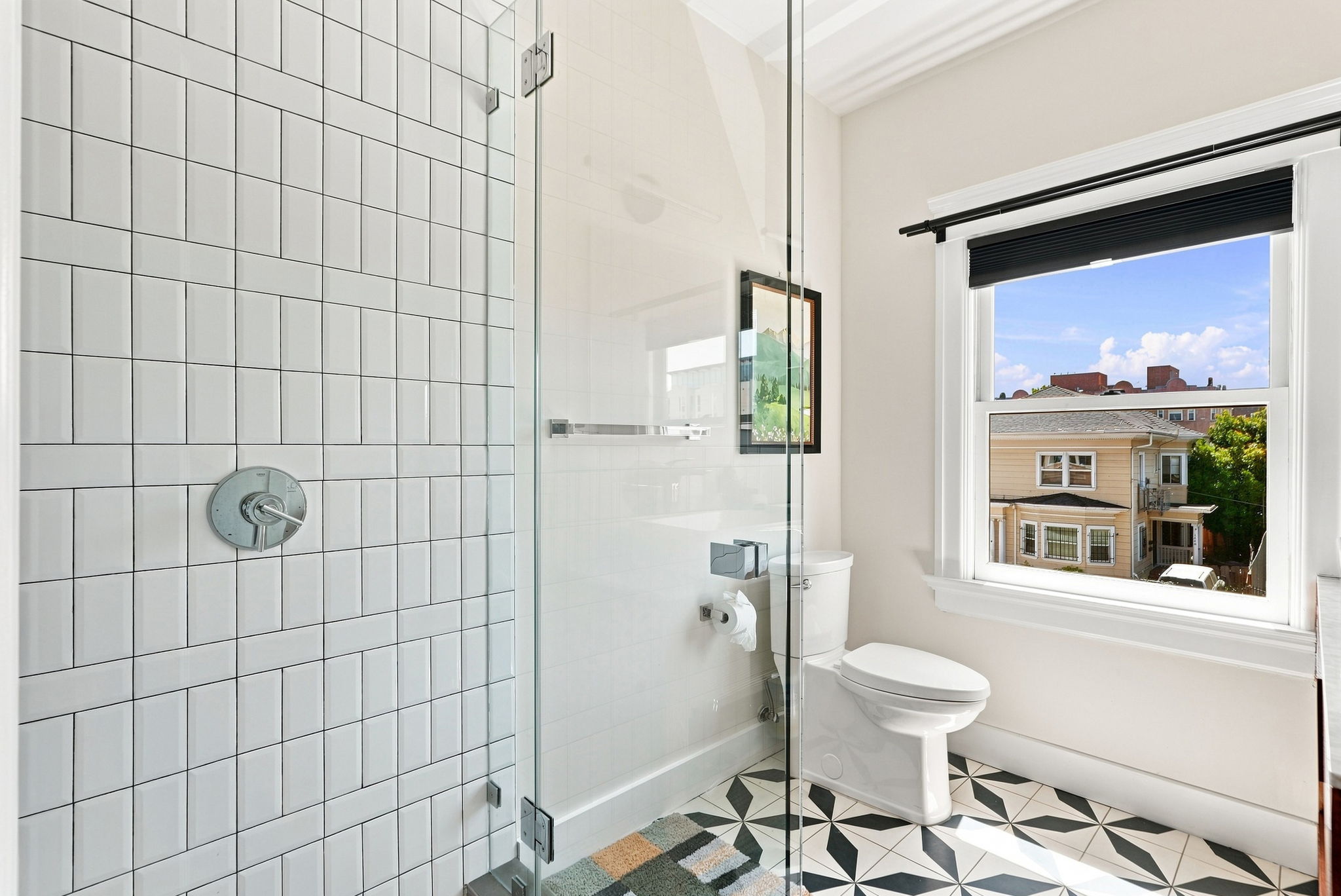 Bright modern bathroom with glass shower and stylish geometric tile