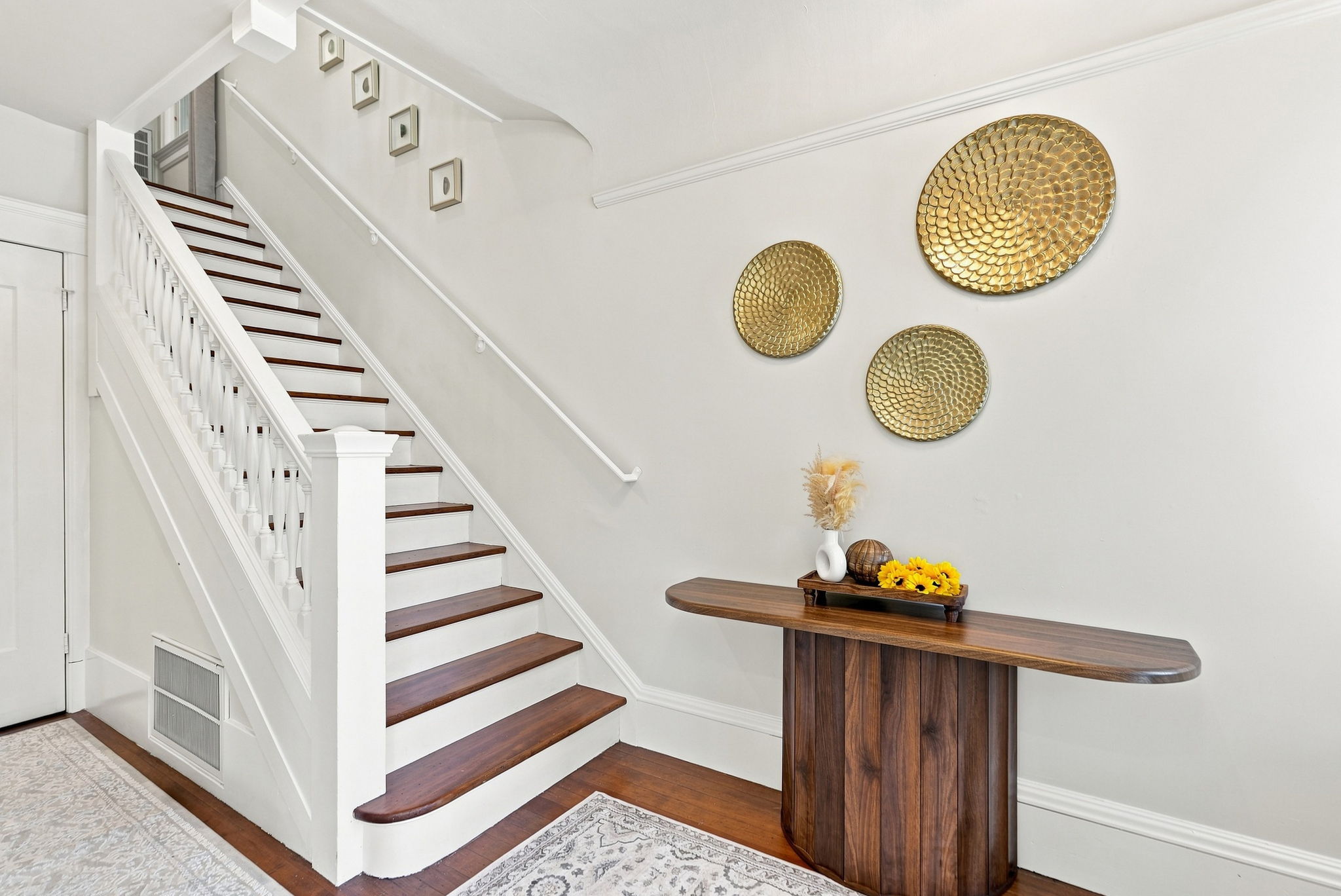 Bright, elegant entryway with stylish staircase and warm wood accents