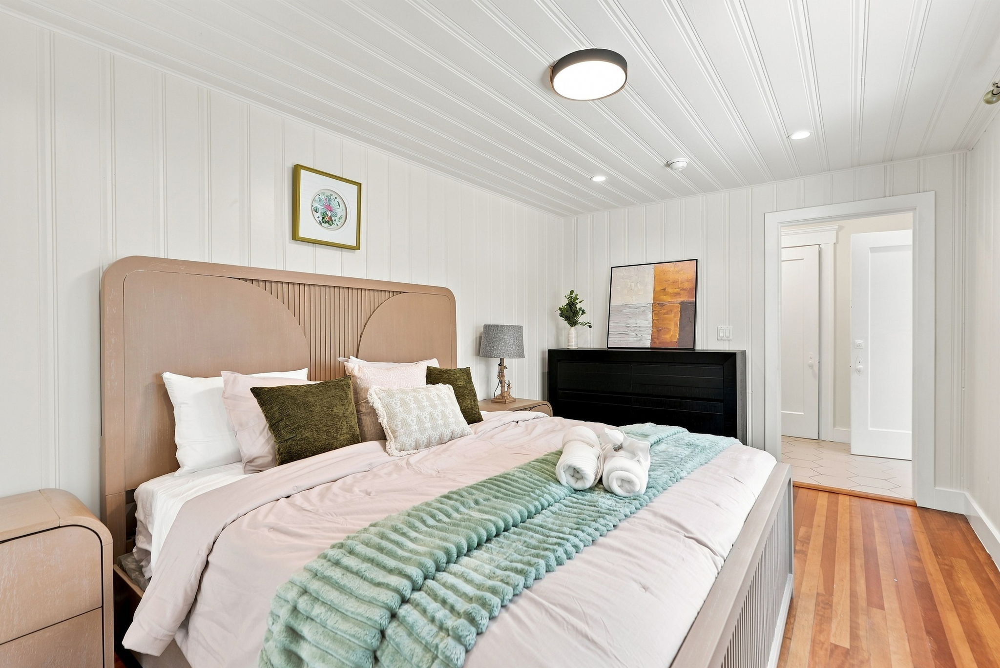 Bright, cozy bedroom with plush king bed and warm wood floors