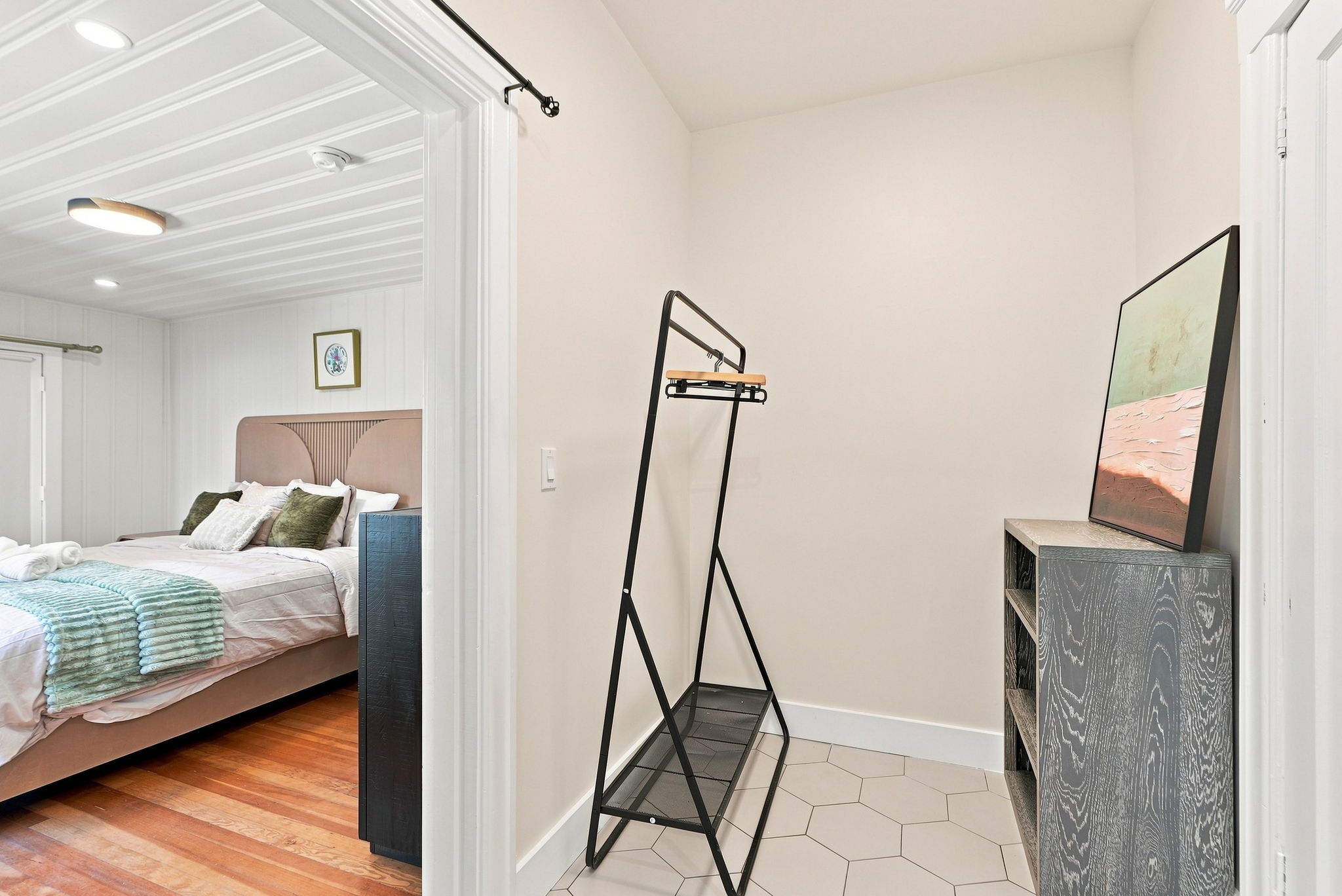 Bright dressing nook with storage beside a cozy, stylish bedroom
