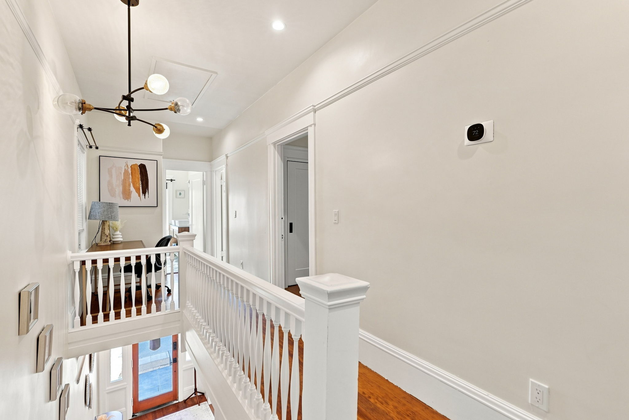 Bright upper landing with high ceilings, hardwood floors, and modern style