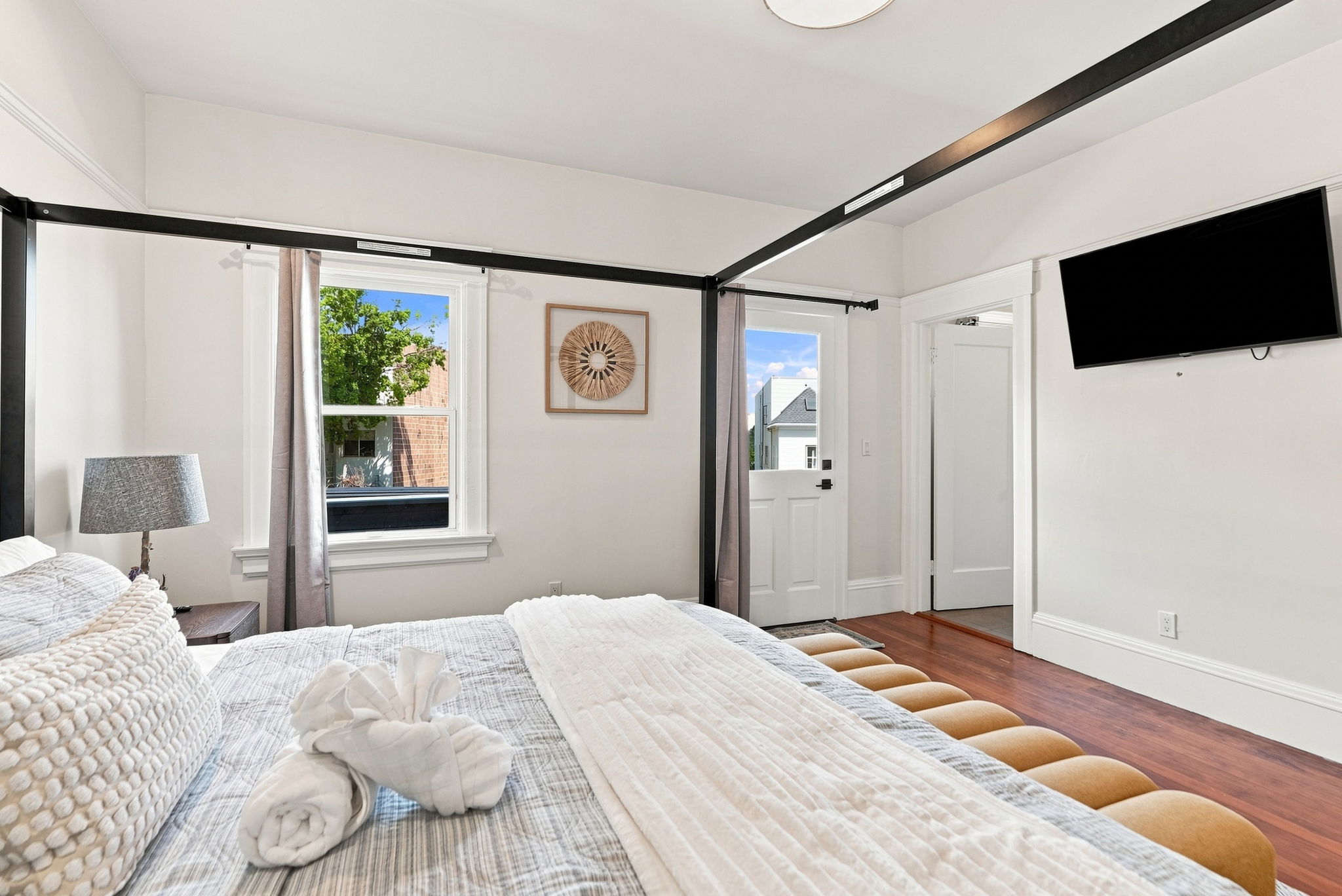 Bright, stylish bedroom with four-poster bed and wall-mounted TV