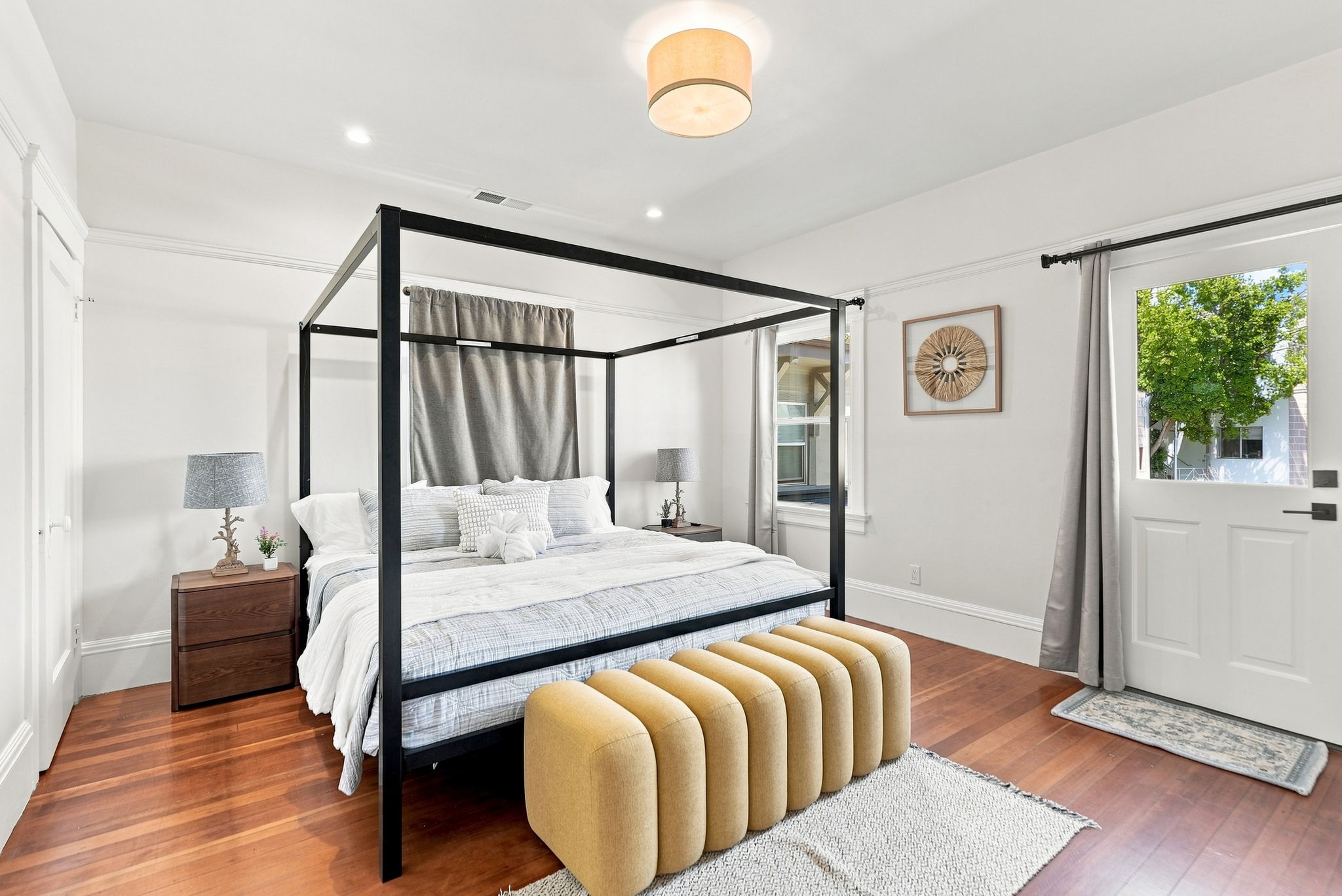 Bright modern bedroom with a chic four-poster bed and warm wood floors