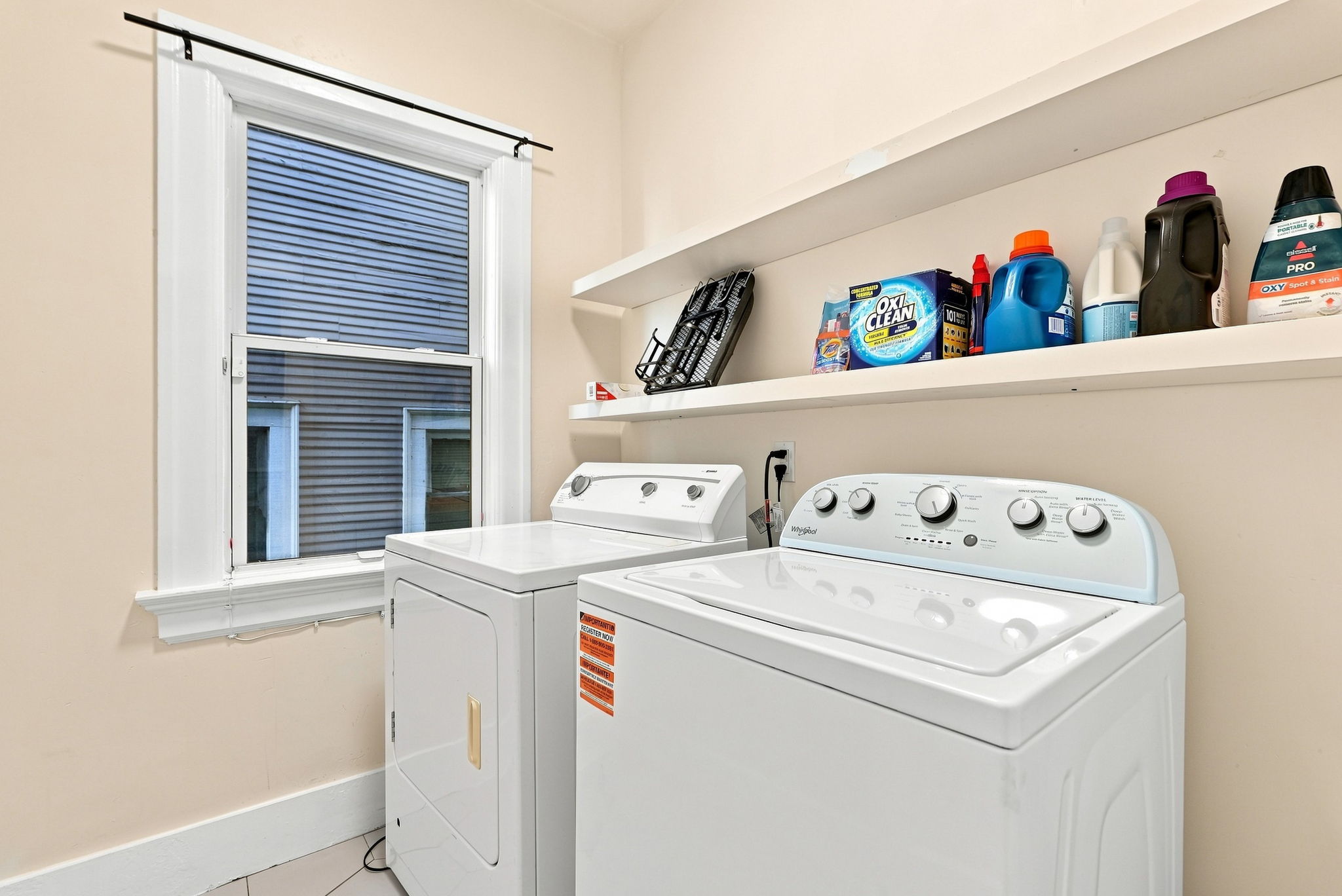 Bright in-home laundry room with full-size washer, dryer, and storage